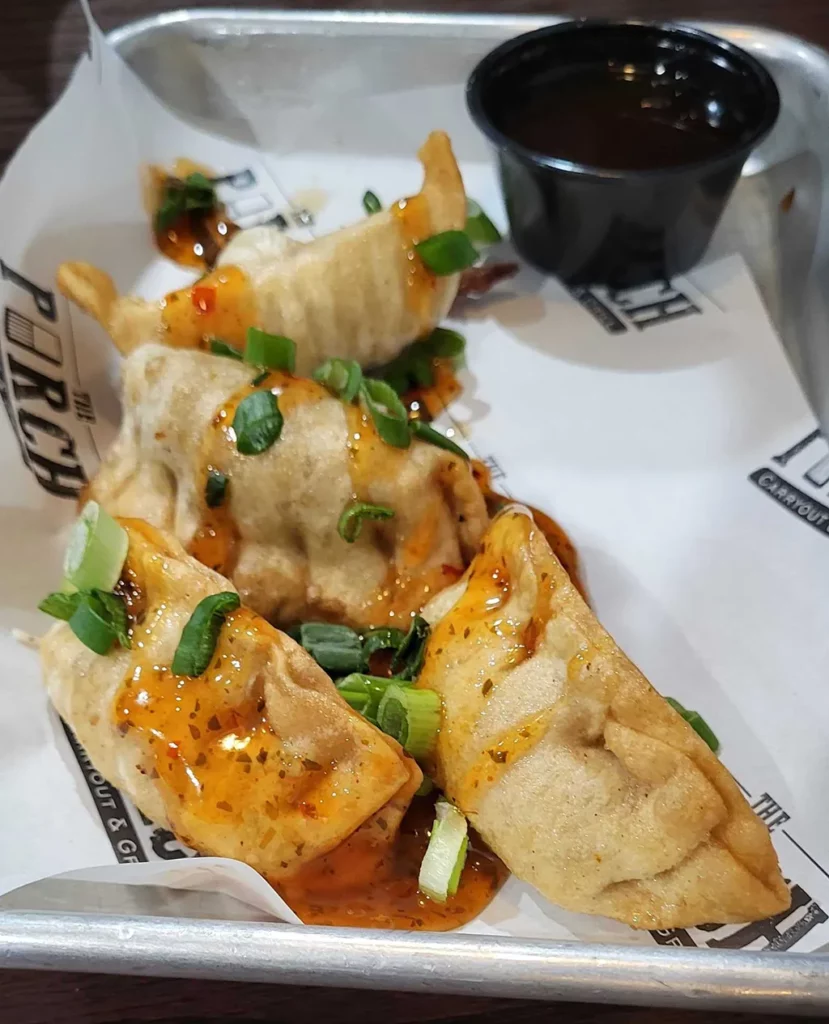 The Porch Carryout & Grill Potstickers. Crispy pork potstickers. Topped with sweet Thai Chili sauce & served with Stinging Honey Garlic Sauce.